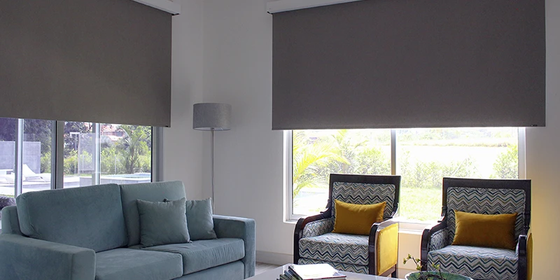Habitación moderna con persiana blackout parcialmente bajada, permitiendo el paso de luz difusa para un ambiente cálido y acogedor."