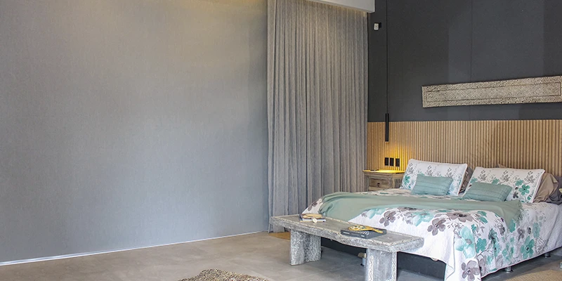 Dormitorio moderno con cortinas blackout oscuras completamente cerradas, creando un ambiente cálido y oscuro ideal para el descanso.