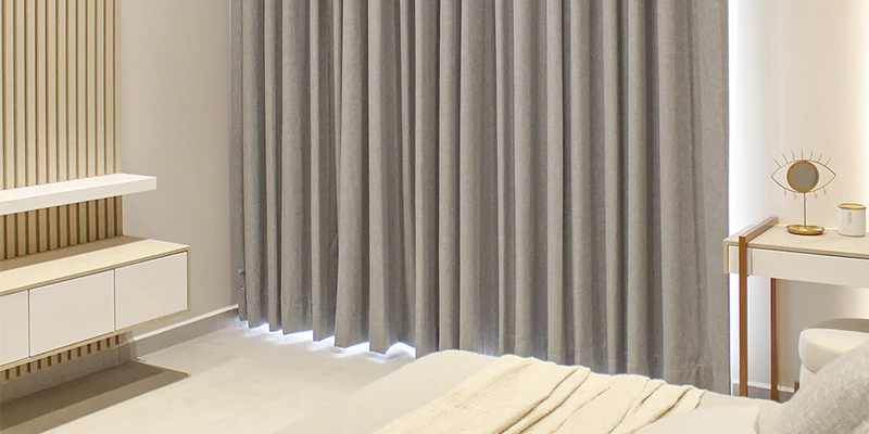 Dormitorio moderno con cortinas blackout oscuras completamente cerradas, creando un ambiente cálido y oscuro ideal para el descanso.
