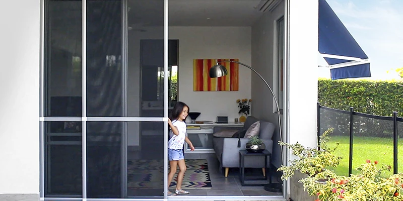 Persona abriendo una pantalla de ventana con un mango negro, mostrando la importancia de los mosquiteros en el hogar.