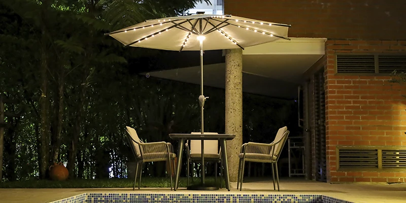 Parasol iluminado junto a la piscina en un jardín al atardecer
