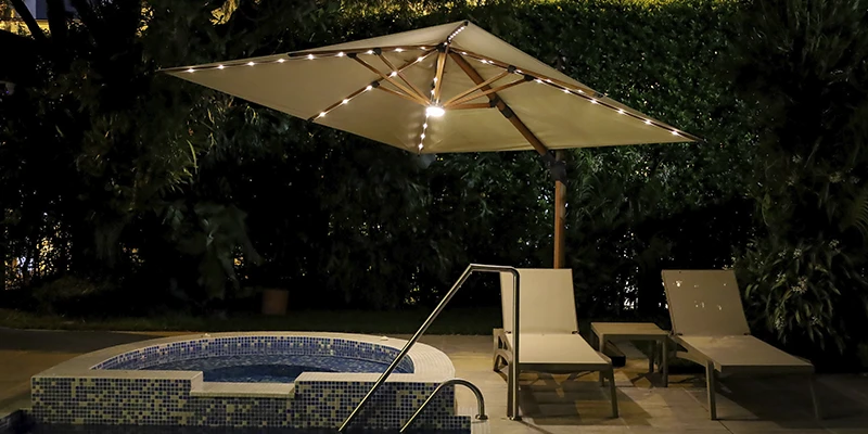 Parasol iluminado junto a la piscina en un jardín al atardecer