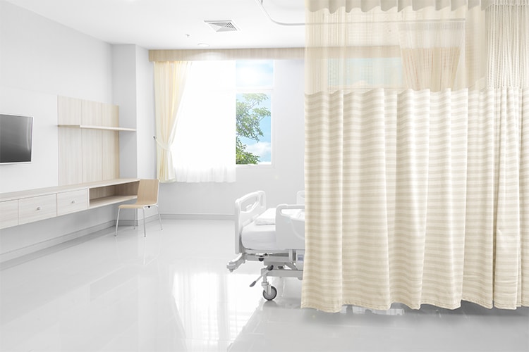 Cortina hospitalaria beige separando el área de camilla en una sala clínica