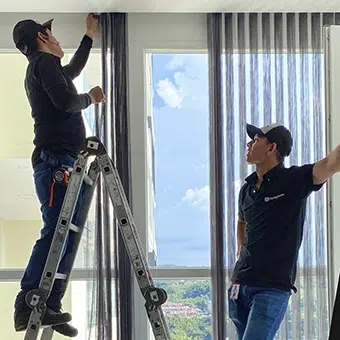 Dos trabajadores Pentagrama, instalando unas persianas Pentagrama