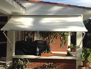 Toldo de brazos fijos en color blanco desplegado en el área de una terraza de una casa campestre