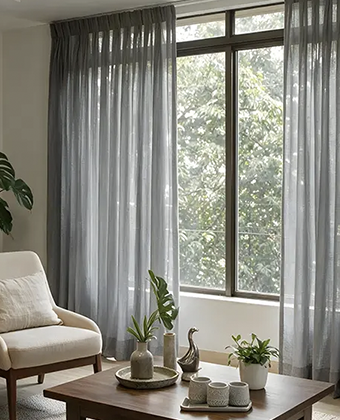 Cortinas ZigZag en tela gris translúcida cubriendo un ventanal, en una sala con vista al jardín