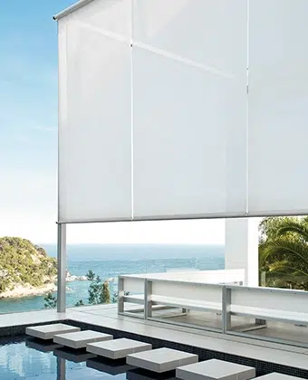 Toldos verticales Atos en tela blanca protegiendo una terraza con vista al mar