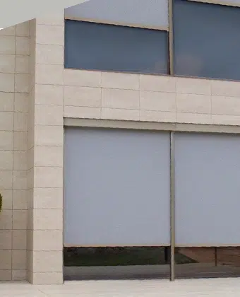 Persianas exteriores Z-Box instaladas en los ventanales de una fachada de piedra