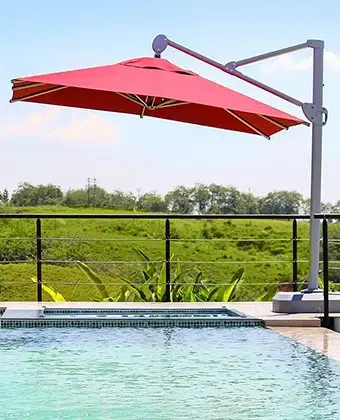 Sombrilla Palma roja junto a una piscina con vista al campo
