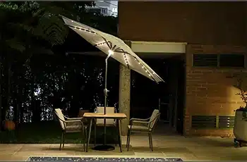 Sombrilla Sicilia iluminada de noche sobre una mesa con sillas